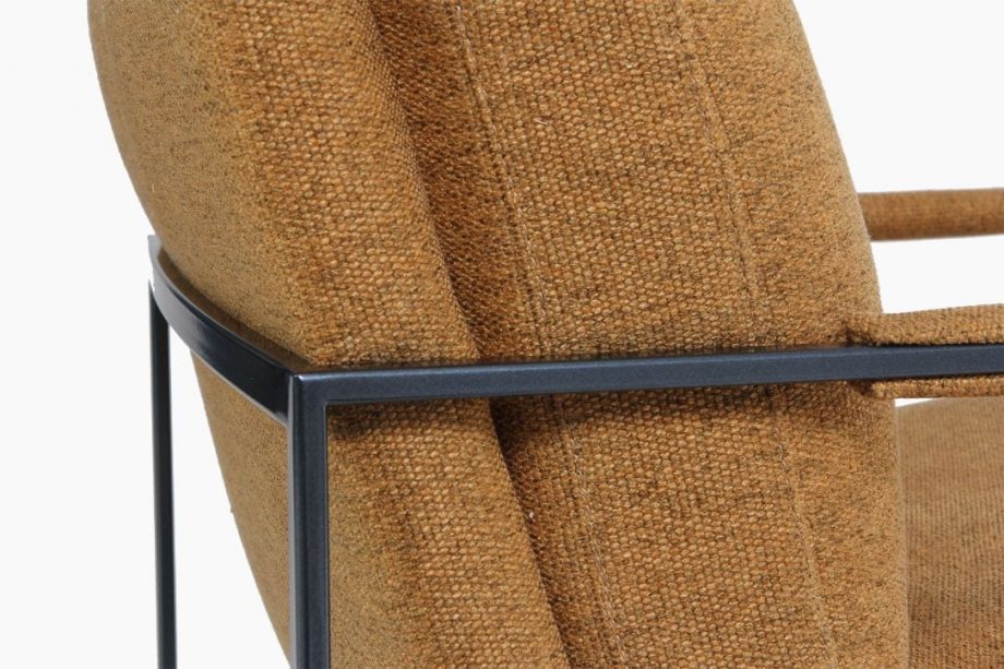 Fauteuil design bij Houweling Interieur. Het is een moderne fauteuil met minimalistisch stalen frame uitgevoerd in oranje bruine stof.
