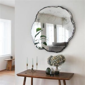 Design spiegel van DeKnudt boven een lage houten wandtafel met accessoires. De decoratieve spiegel koop je bij Houweling Interieur.