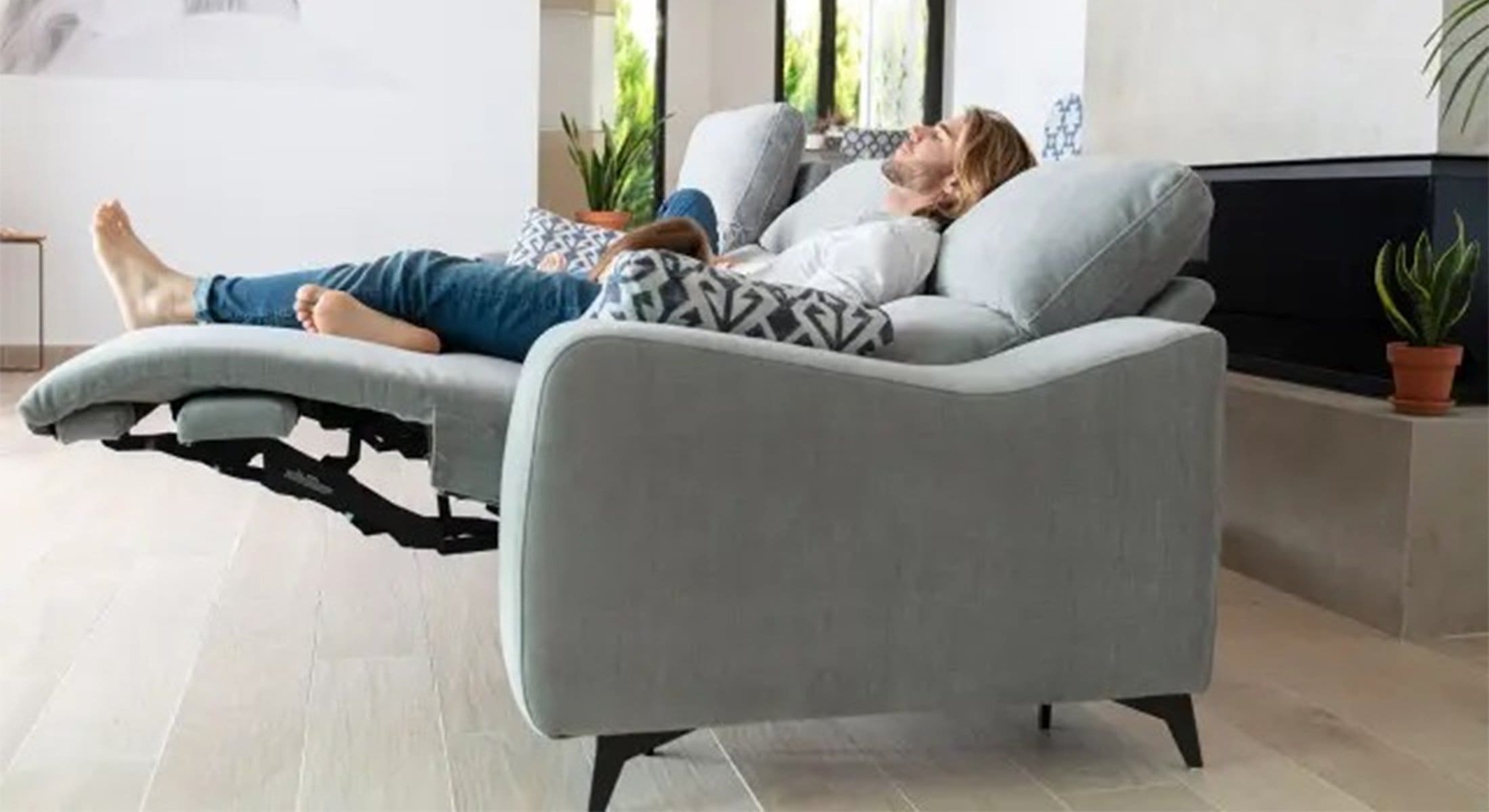 Relaxbank bij Houweling Interieur. Het is een bank met relaxfunctie uitgevoerd in grijze stof.