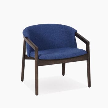 Lounge fauteuil bij Houweling Interieur. Het is een design fauteuil uitgevoerd in blauwe stof en donkerhout armen en poten.