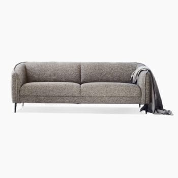 Design bank van Flexlux bij Houweling Interieur. Het is een 3-zitsbank met zachte lijnen uitgevoerd in grijze stof.