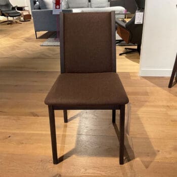 Showroom model van eetkamerstoelen van Skovby bij Houweling Interieur. Het zijn houten eetkamerstoelen met bruine stof.