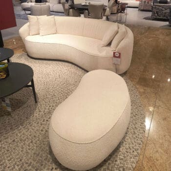 Showroom model een design bank met poef bij Houweling Interieur. Moderne bank met ronde vormen in crème stof.