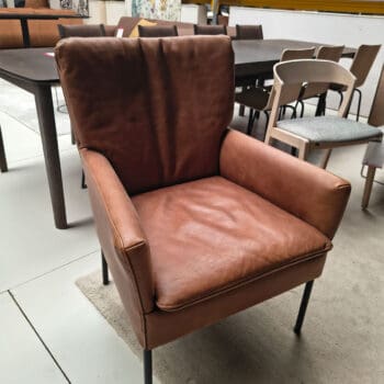 Showroommodel van een leren fauteuil bij Houweling Interieur. Moderne fauteuil uitgevoerd in cognac leer en zwarte ranke poten.