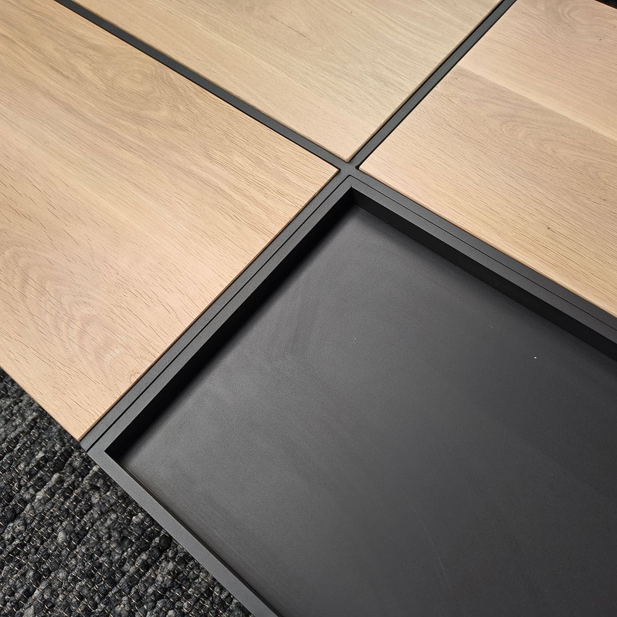 Showroommodel van een houten salontafel bij Houweling Interieur. Design salontafel uitgevoerd in antraciet stof.