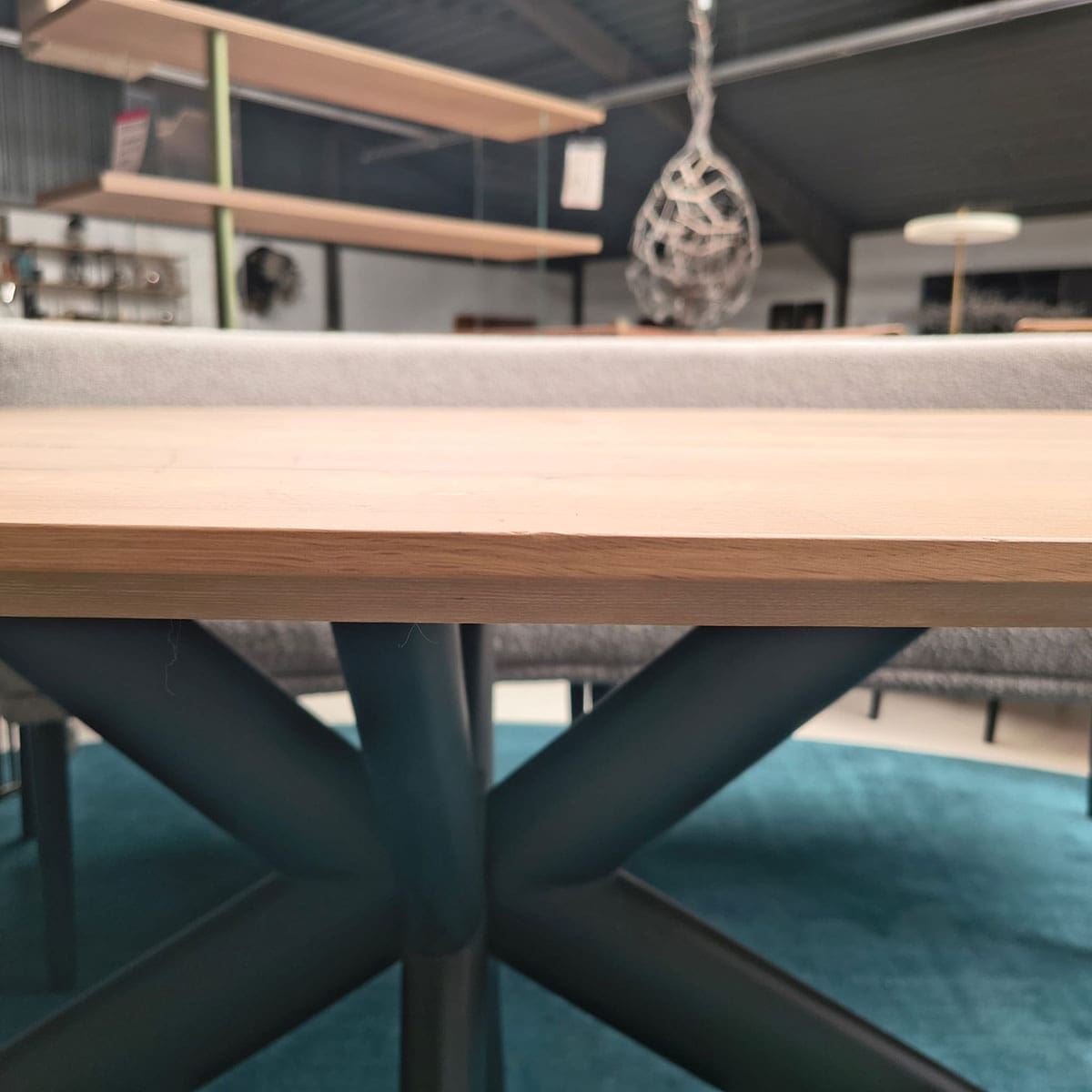 Showroommodel van een ovale eettafel bij Houweling Interieur. Houten eettafel uitgevoerd met bruinmetalen spinpoot.