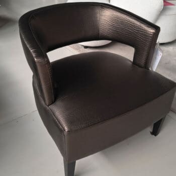 Showroommodel van leren design fauteuil bij Houweling Interieur. Moderne fauteuil uitgevoerd in glimmend bruin leder.