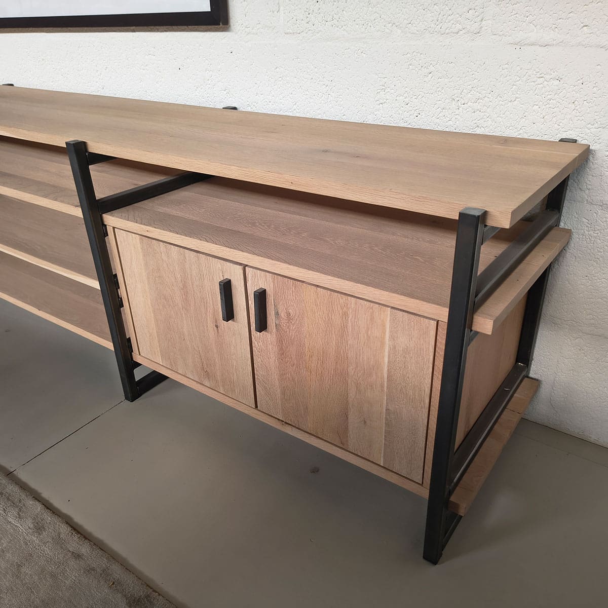 Showroommodel van eikenhouten tv meubel bij Houweling Interieur. Houten dressoir uitgevoerd in eiken met metalen afwerking.