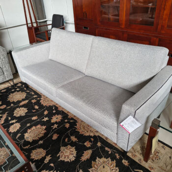Showroommodel van design bank bij Houweling Interieur. Moderne bank uitgevoerd in lichtgrijze stof met bies.