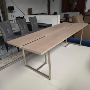 Showroommodel van houten eettafel bij Houweling Interieur. Moderne eettafel uitgevoerd met beige eikenhout blad en rvs onderstel.