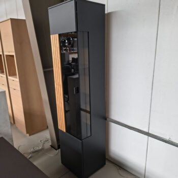 Showroommodel van vitrinekast bij Houweling Interieur. Smalle wandkast uitgevoerd met houten lamellen en hoekbeglazing.