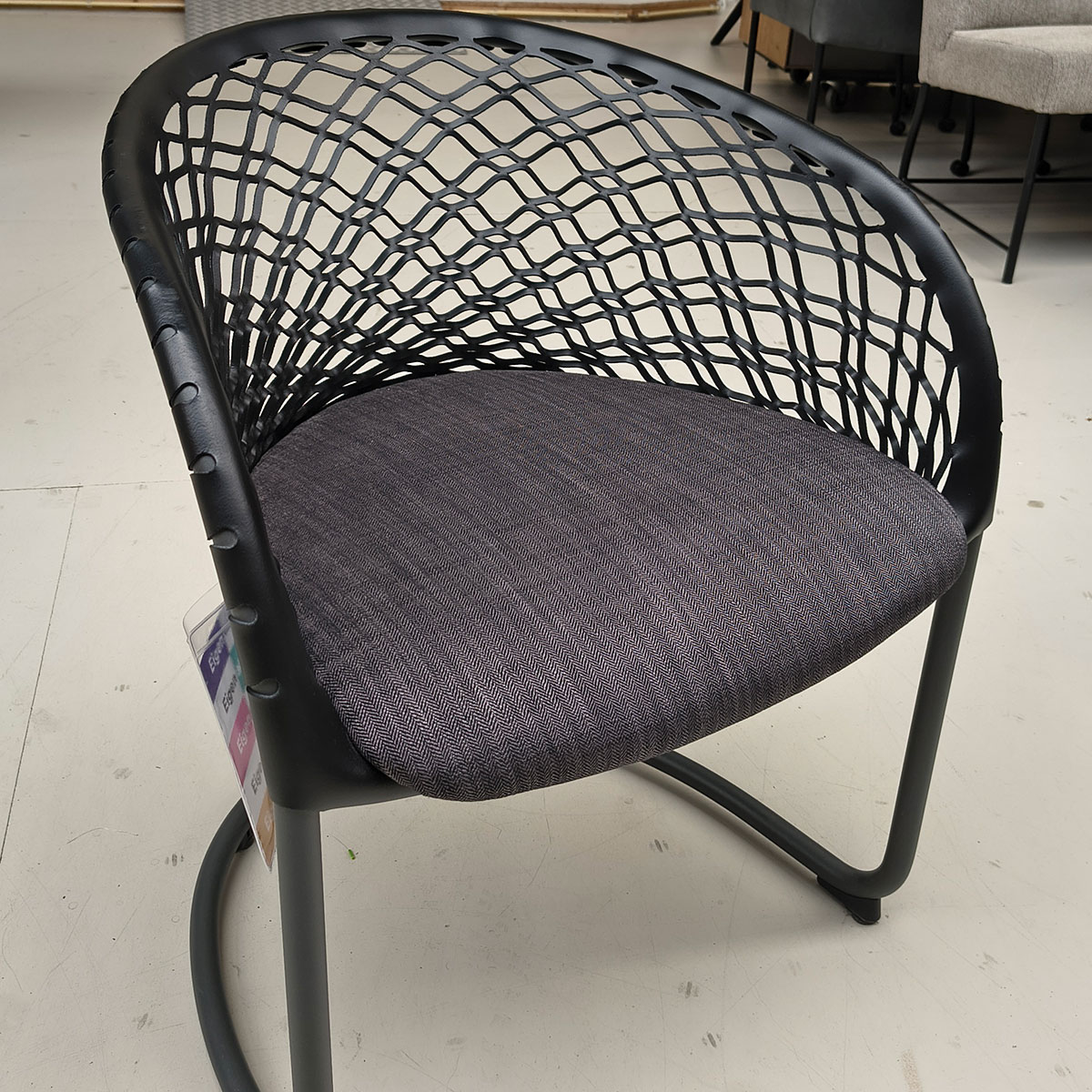 Showroommodel van design eetkamerstoel bij Houweling Interieur. Moderne eetkamerstoel met leren leuning en grijs kussen.