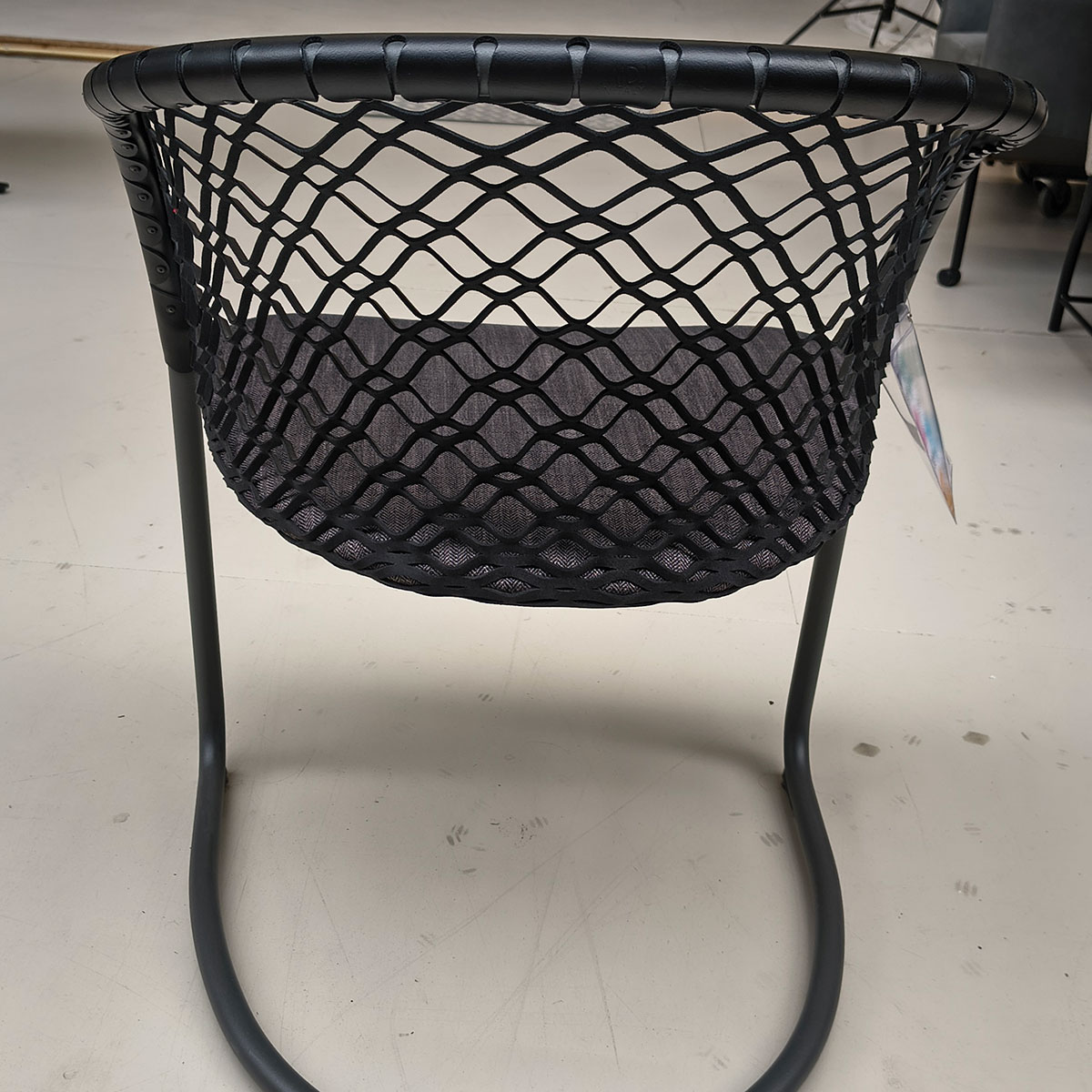 Showroommodel van design eetkamerstoel bij Houweling Interieur. Moderne eetkamerstoel met leren leuning en grijs kussen.