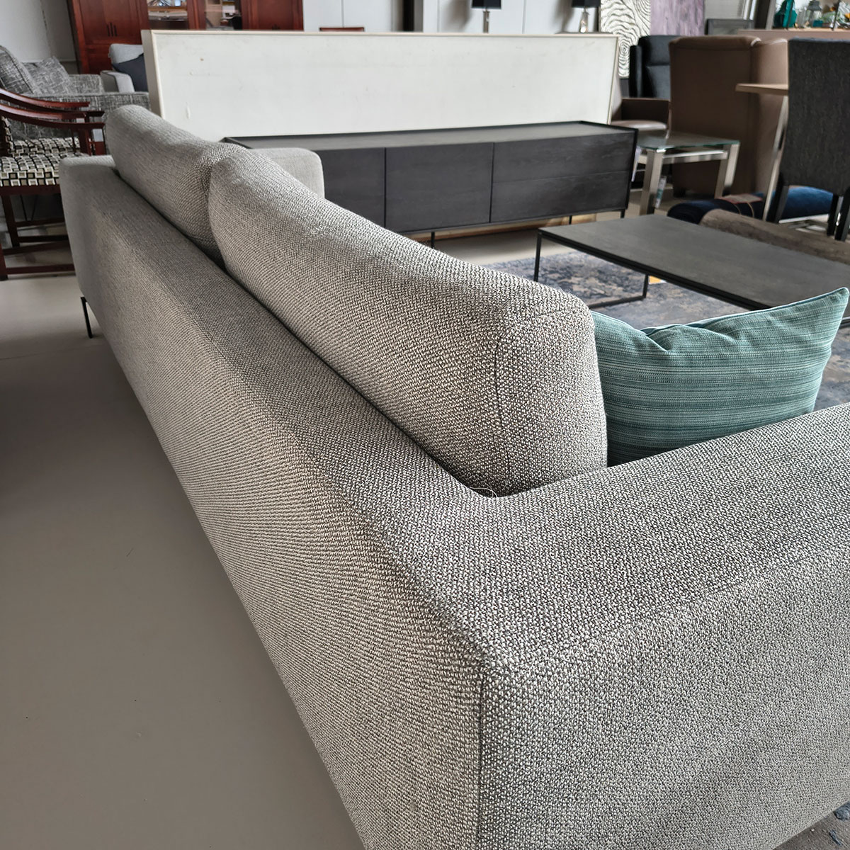 Showroommodel van een 4-zitsbank bij Houweling Interieur. Moderne bank uitgevoerd in lichtgrijze stof en zwarte ranke poten.